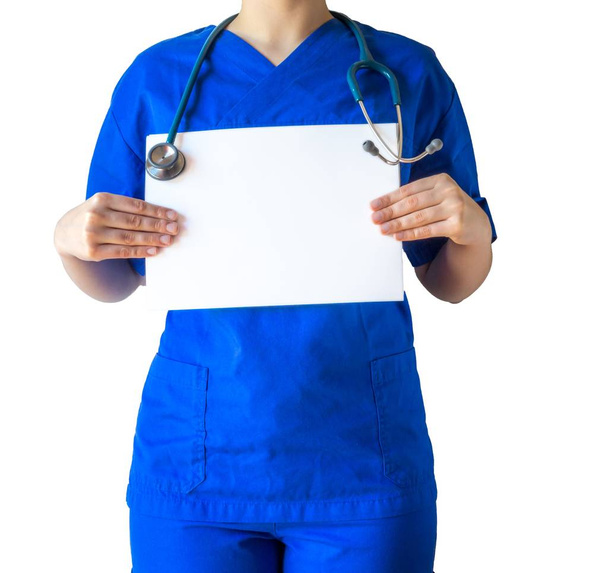 Young female doctor in a blue medical uniform holding a blank white paper with a copy space - Foto, Imagem