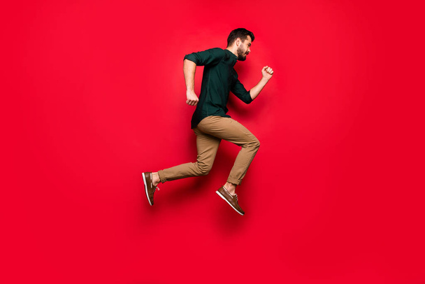 Full size photo of confident guy jump run want be fast buy all spring time discounts wear brown pants trousers isolated over vibrant color background - Zdjęcie, obraz