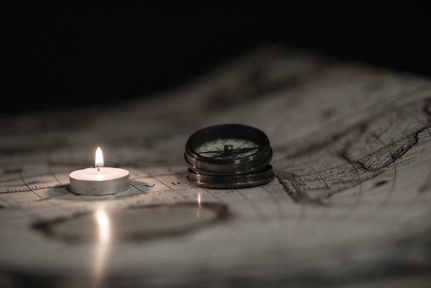 sesion con velas brujula y mapa en fondo negro - Foto, Imagem