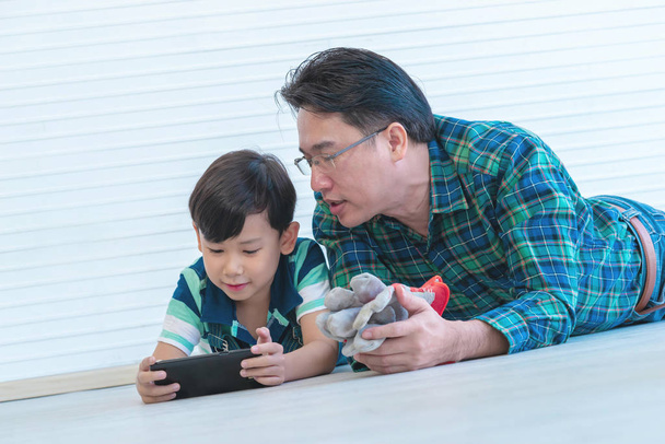 Isä ja poika käyttävät älypuhelinta yhdessä nykyaikaiseen famil
 - Valokuva, kuva