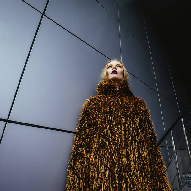 young beautiful  woman in faux fur coat posing on street - Fotografie, Obrázek