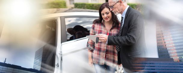 Vendeur de voiture donnant des explications sur tablette à la jeune femme ; multi
 - Photo, image