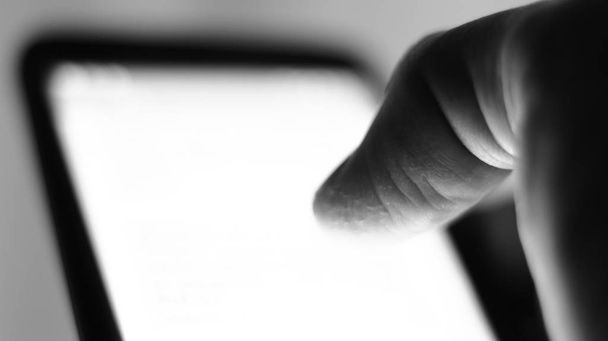 Macro egy férfi ujj, miközben csúszik, ellenőrzés, kezelése mobiltelefon. - Fotó, kép