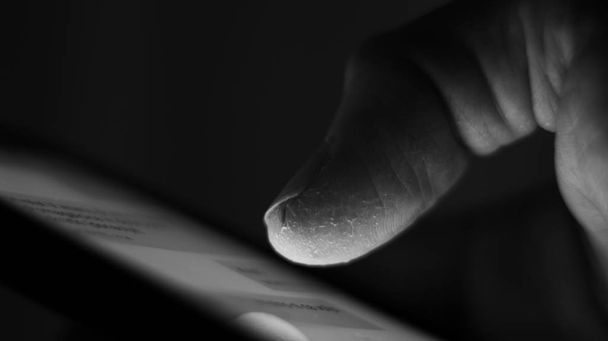 Macro of a male finger, while sliding, checking, handling mobile phone. - Photo, Image