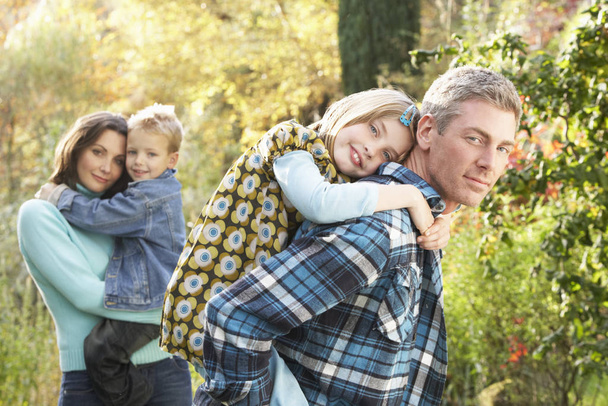 Family Group Outdoors In Autumn Landscape With Parents Giving Chiildren Piggybac - Foto, imagen