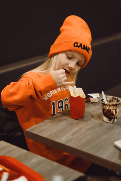 children at mcdonald's. Little girl eats french fries and drinks - Foto, imagen