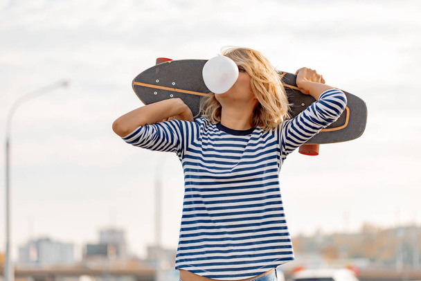 Urban stylish young girl walking with skateboard. Outdoors portr - Zdjęcie, obraz