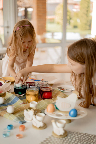 Mother and her daughters painting eggs. Happy family preparing for Easter. - Photo, image