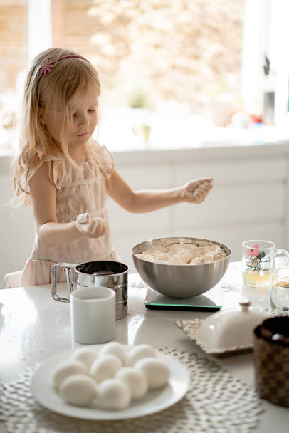 girl helps mom in the kitchen to cook Easter cakes.  Happy family preparing for Easter - Photo, image