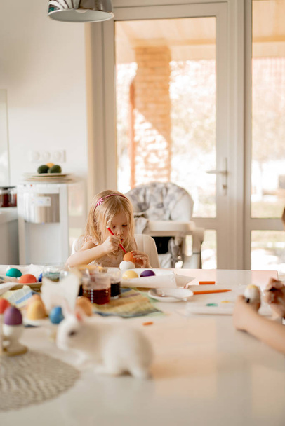 Mother and her daughters painting eggs. Happy family preparing for Easter. - Foto, Bild