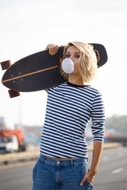 Urban stylish young girl walking with skateboard. Outdoors portr - Fotoğraf, Görsel