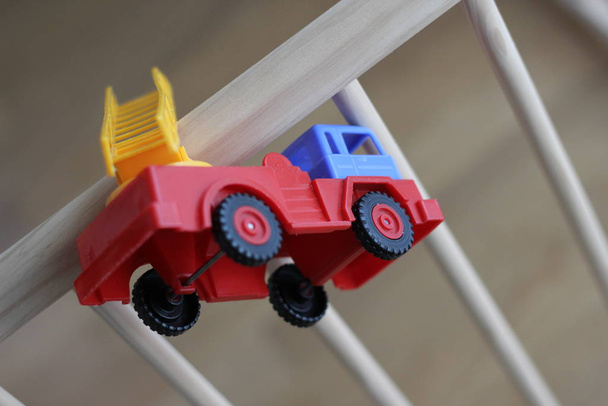 Carro de brinquedo de bebê de plástico pequeno bombeiro em um berço de madeira. Para jogar. Por diversão
. - Foto, Imagem