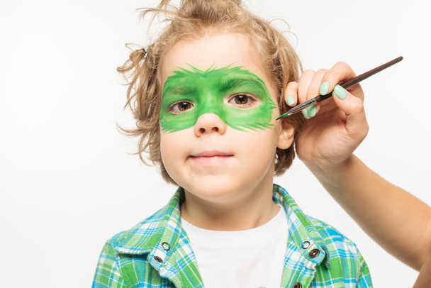partial view of artist painting gecko mask on face of adorable boy isolated on white - Fotoğraf, Görsel