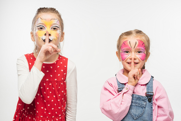 adorable friends with cat muzzle and butterfly paintings on faces showing hush sign isolated on white - Fotografie, Obrázek