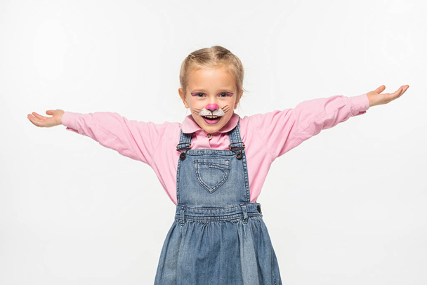 positive child with cat muzzle painting on face standing with open arms while looking at camera isolated on white - Foto, afbeelding