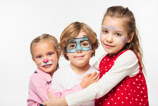 happy friends with colorful face paintings embracing while looking at camera isolated on white - Photo, Image