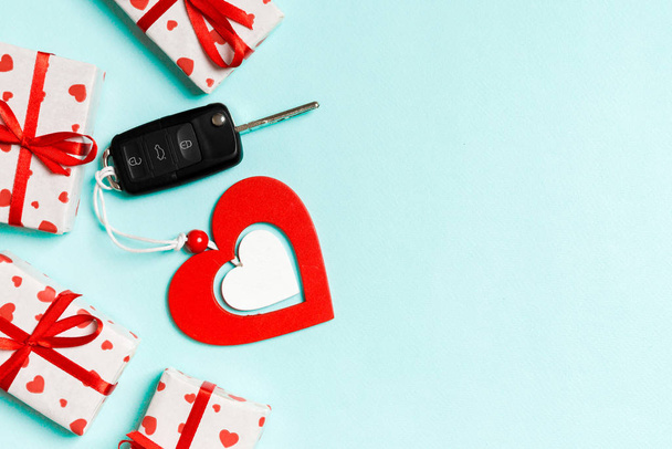 Κάτοψη του κλειδιού του αυτοκινήτου, κουτιά δώρων και ξύλινη καρδιά σε πολύχρωμο φόντο. Άγιος Βαλεντίνος έννοια με αντίγραφο χώρου - Φωτογραφία, εικόνα