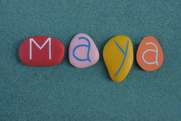 Maya, ženské jméno složené z různobarevných a vyřezávaných kamenných písmen nad zeleným pískem - Fotografie, Obrázek