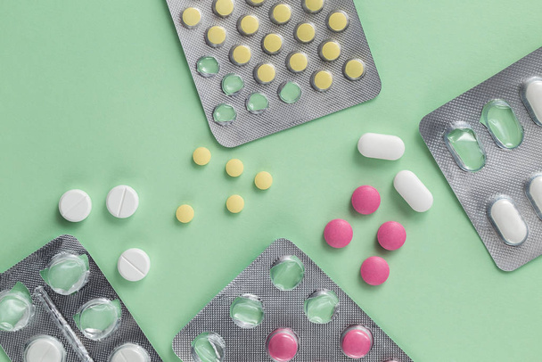 Medicamentos de farmácia, comprimidos em embalagens em um fundo verde simples, analgésicos e outros produtos médicos
 - Foto, Imagem