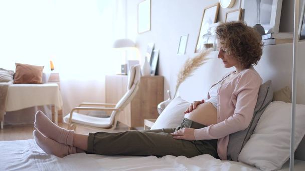 Pregnancy Concept. Pregnant Woman Sitting On Bed At Home In Bedroom. - Foto, imagen