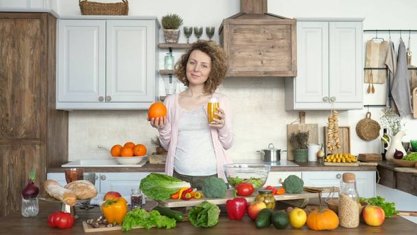 Pregnancy And Healthy Diet Concept. Pregnant Woman With Orange Juice On Kitchen. - Фото, изображение