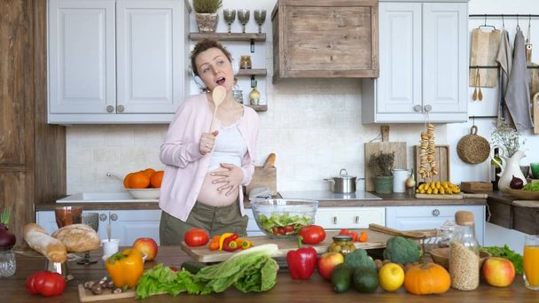Happy Pregnancy Concept. Cheerful Pregnant Girl Dancing And Singing In Kitchen. - Photo, image