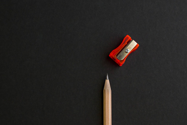 Natural wood pencil on the black surface with red color sharpener.Space for text,conceptual image of education. - Foto, Imagem