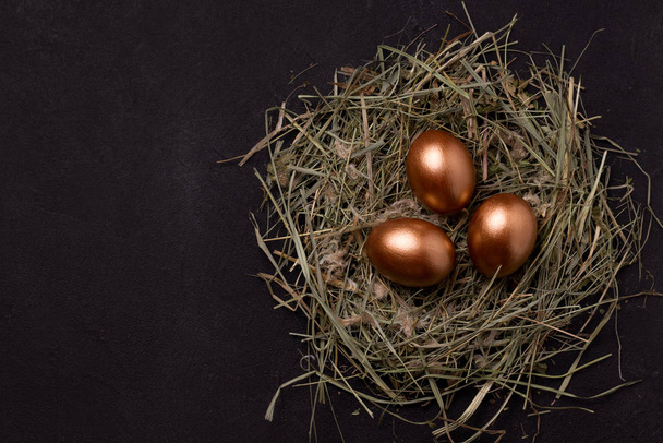 copper colored easter eggs on a black background in a nest of hay. Have copy spaces - Foto, Bild