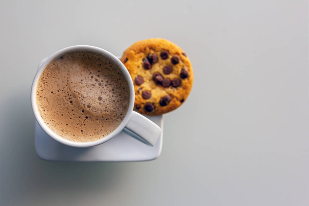 A cup of cappuccino cofee with cookie on a saucer. Copy space. Light background - 写真・画像