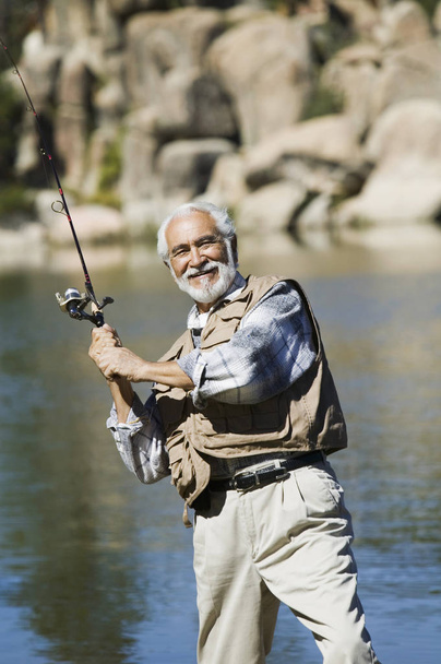 senior man fishing with rod in the river - Foto, afbeelding