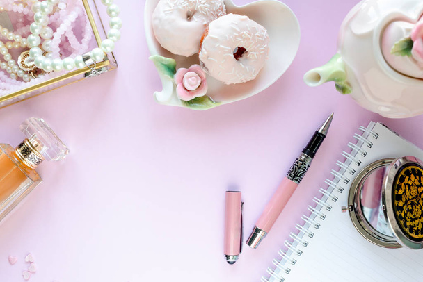 Fashion blogger werkruimte met laptop en vrouwelijk accessoire, cosmetica producten op lichtroze tafel. Snoep, donuts, macarons en geschenken voor de Valentijnsdag. vlakke lay, bovenaanzicht - Foto, afbeelding