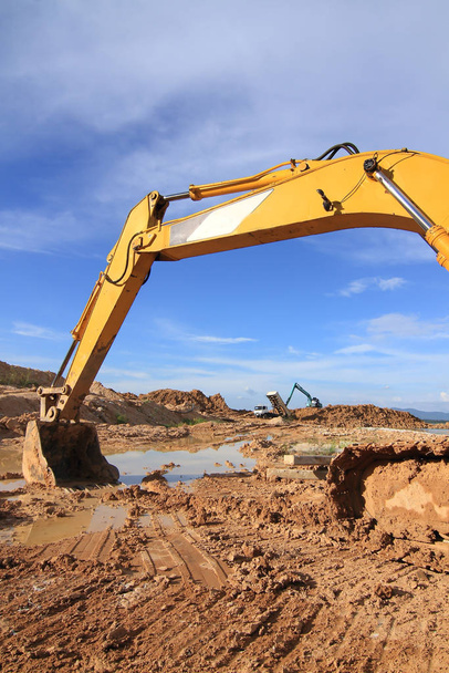 Máquina escavadora carregadora durante trabalhos de terraplanagem ao ar livre no local de construção
 - Foto, Imagem