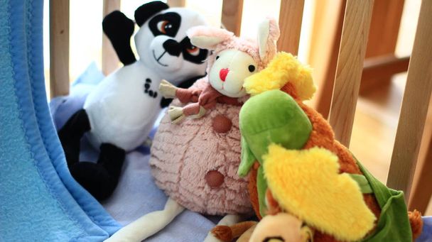 Яскраві плюшеві іграшки в дитячому ліжечку
. - Фото, зображення