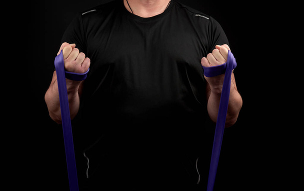 Sportler mit muskulösem Körper in schwarzer Kleidung macht körperliche Anstrengungen  - Foto, Bild