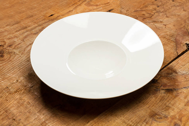 Un plato blanco profundo sobre una mesa de madera rústica en una vista superior
 - Foto, Imagen