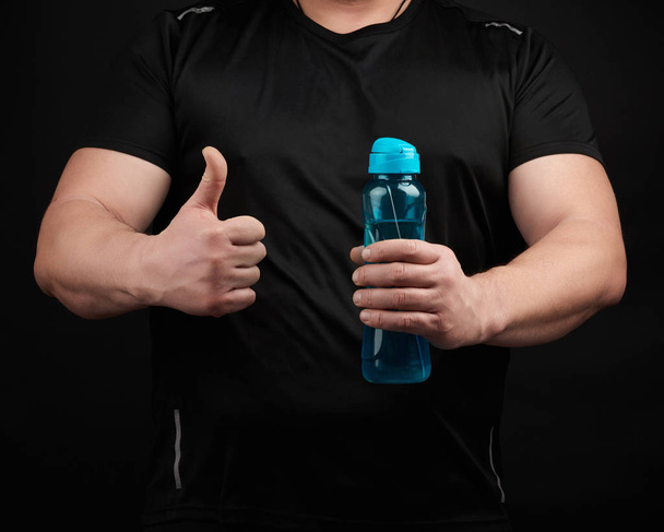 筋肉を持つ成人男性アスリートはペットボトルを持っています - 写真・画像