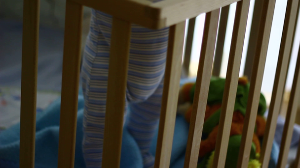 Uit focus van een houten babybedje met baby erin spelend. Eenzaam. Alleen..  - Video