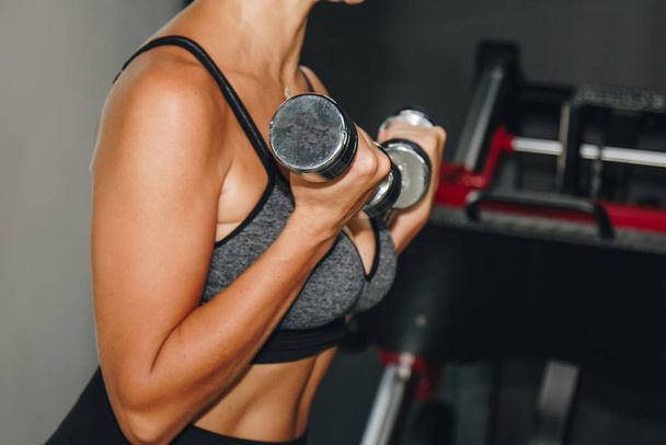 sport, fitness, bodybuilding, weightlifting and people concept - close up of woman flexing arms with dumbbell in gym. - Foto, Imagen