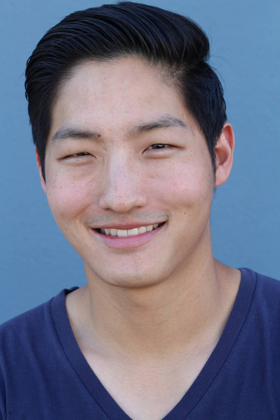 közeli kép egy jóképű fiatal ázsiai férfiról kék ingben a kék fal előtt - Fotó, kép