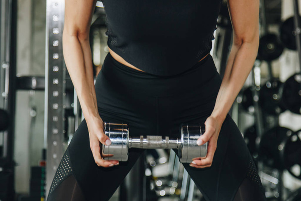 sport, fitness, bodybuilding, weightlifting and people concept - close up of woman flexing arms with dumbbell in gym. - Photo, image