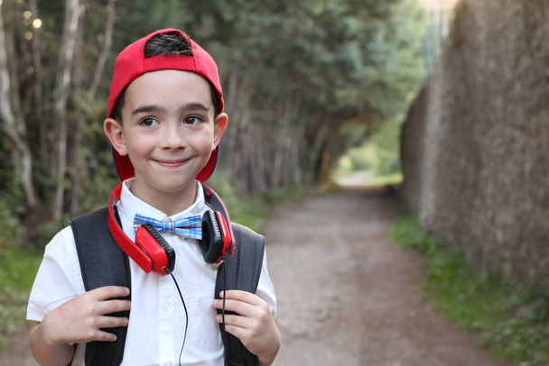 Κοντινό πλάνο πορτρέτο του κομψό παιδί αγόρι με κόκκινα ακουστικά στέκεται σε εξωτερικούς χώρους  - Φωτογραφία, εικόνα