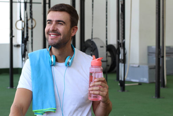 Чоловік використовує багаторазову пластикову пляшку води в спортзалі
 - Фото, зображення