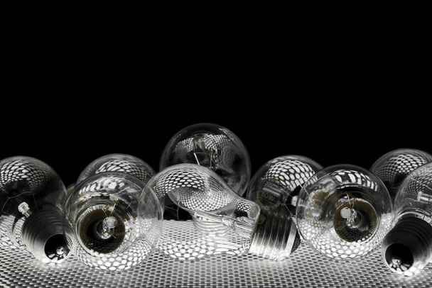 heap of clear lightbulbs with circular reflections, black background - Фото, изображение