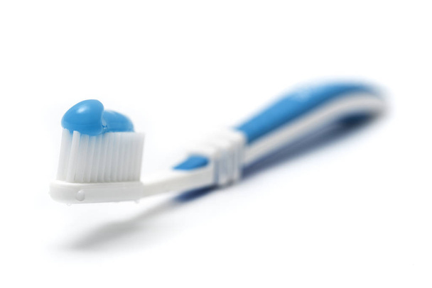toothbrush with blue toothcream on white surface, shallow depth of field - Fotó, kép