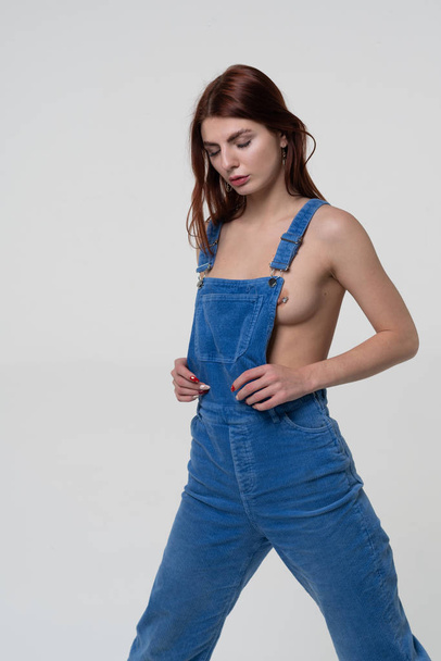 young beautiful girl stands in blue overalls - Φωτογραφία, εικόνα