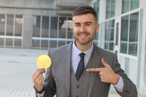 close-up portrait of handsome young businessman holding golden medal on street - Foto, Imagen