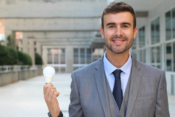Empresário mostrando lâmpada no prédio de escritórios
 - Foto, Imagem