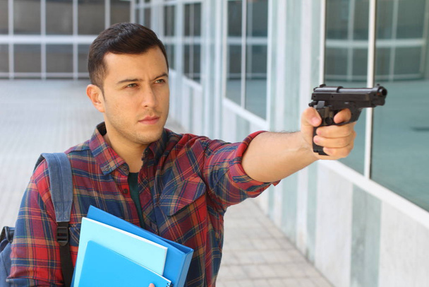 close-up portrait of handsome young man with backpack and folders holding gun - Photo, Image