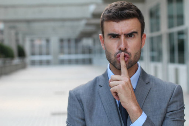 Homme utilisant un signe du doigt pour demander à quelqu'un de garder le silence
 - Photo, image