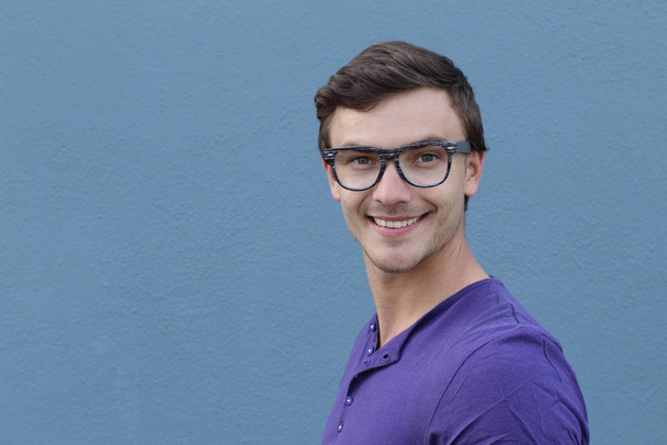 közeli kép egy jóképű fiatalemberről lila ingben a kék fal előtt - Fotó, kép